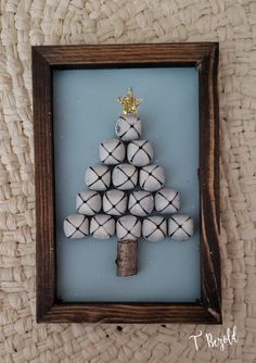 a small christmas tree made out of toilet paper rolls in a wooden frame on a wall