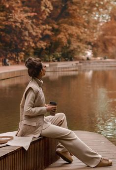 a woman sitting on a dock drinking coffee