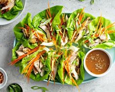 lettuce with carrots and sauce on a plate next to small bowls of dipping sauce