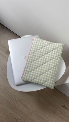 a green and white blanket sitting on top of a white chair next to a wall