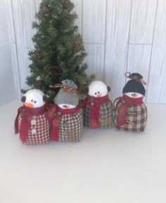 three snowmen are standing next to a christmas tree