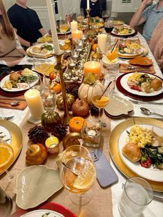 a long table is set with plates, silverware and candles for an elegant thanksgiving dinner