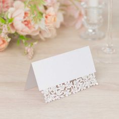 a table topped with pink flowers and white place cards on top of a wooden table