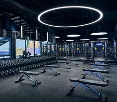 an empty gym with rows of benches and treadmills