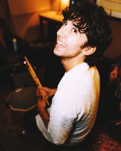 a man sitting on the floor holding a guitar