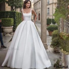 a woman in a white wedding dress standing on the sidewalk