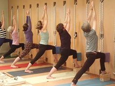 a group of people doing yoga poses in front of a wall with ropes on it