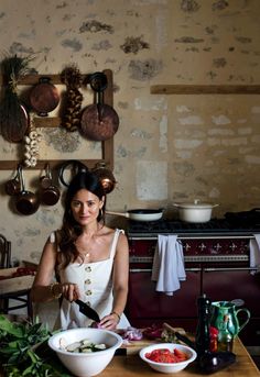 a woman standing in front of a wooden table with bowls and utensils on it