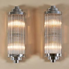 two chrome and glass wall lights on a beige wall with dim lighting in the middle