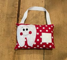 a red and white polka dot bag with a tooth on it