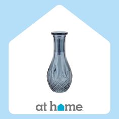 a clear glass vase sitting on top of a blue and white sign that says at home