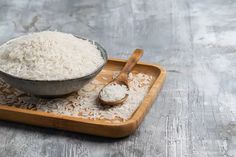 white rice in a bowl and spoon on a wooden tray