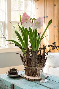 a vase with flowers in it sitting on a table next to a bird and nest