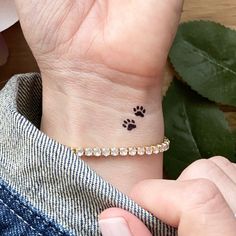 a woman's wrist with a small dog paw tattoo on the left side of her arm