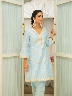 Set of 3 consists of kurta, pant and inner. Noor, bringing the magic of festivities straight to your closet in shades of pastels. Kurta: A elegant powder blue short chanderi kurti with heavy gota lace detailing on the neckline, sleeves & hemline. Comes with an inner. Pants: Straight fit cotton silk pants adorned with gota detailing. Occassion: Day Wear, Evening Wear, Festive Wear Fabric: Chanderi Wash Care Instructions: Dry Clean Only Note: The product will be shipped within 15-20 days of th Light Blue Kurta With Zari Work For Diwali, Light Blue Straight Kurta For Diwali, Light Blue Zari Work Kurta For Festivals, Light Blue Chanderi Salwar Kameez For Eid, Light Blue Straight Kurta With Zari Work, Festive Light Blue Kurta With Dabka Work, Blue Straight Kurta Unstitched Suit For Summer, Light Blue Straight Kurta In Bollywood Style, Light Blue Bollywood Style Kurta With Dabka Work