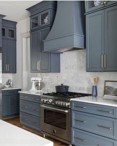 a kitchen with blue cabinets and white counter tops, an oven in the center is surrounded by gray cupboards