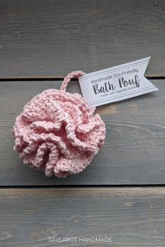 a pink crochet ball with a tag attached to it on a wooden surface