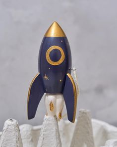 a blue and gold toy rocket sitting on top of white rocks