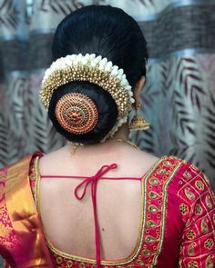 the back of a woman's head wearing a red and gold blouse with an intricate design on it