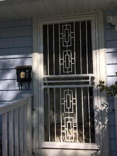 an iron gate is on the front door of a house with white siding and blue walls