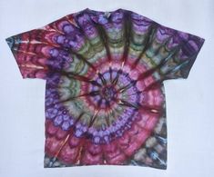 a t - shirt that has been dyed with different colors and patterns on it, sitting on a white surface