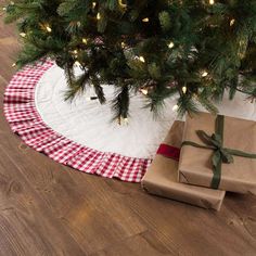 a christmas tree with presents under it on the floor next to a blanket and wrapped present