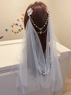 a veiled headpiece with flowers and pearls on the top is sitting in front of a white table