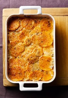 baked potato casserole in a white dish on a wooden tray next to a purple cloth