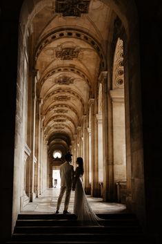 a bride and groom standing on the stairs in an old building