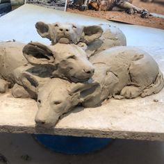 some clay animals are sitting on a table and one is laying down in the sand