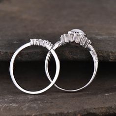 two white gold wedding rings with baguettes and diamonds on them sitting on some rocks