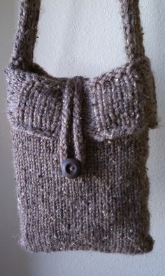 a knitted bag hanging on the wall with a button attached to it's side