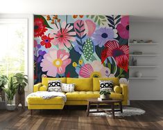 a living room scene with focus on the yellow couch and floral wall mural behind it