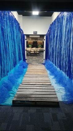 an entrance to a building with blue water flowing down the walls and wood flooring