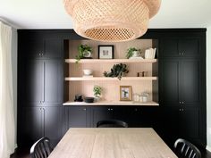 a dining room with black cabinets and a wooden table in front of a wicker light fixture