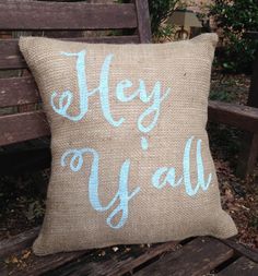 a burlap pillow with the words hey y'all painted on it sitting on a bench