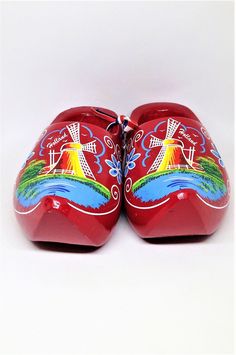 two red shoes with colorful designs on them sitting next to each other in front of a white background