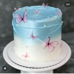 there is a blue cake with pink butterflies on the frosting and white icing