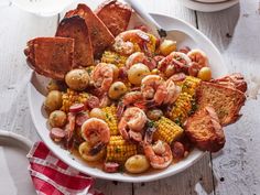 a white bowl filled with shrimp, corn and french toast on top of a wooden table