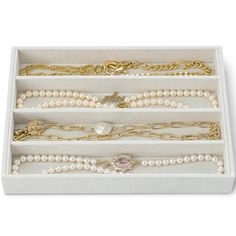 an assortment of pearl necklaces and bracelets in a white box on a white background