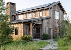 a wooden house sitting in the middle of a lush green field