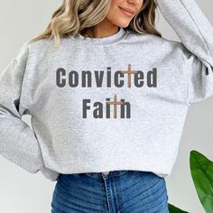 a woman wearing a grey sweatshirt that says,'convieted faith '