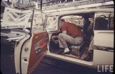 an old photo of a man sitting in the back of a van