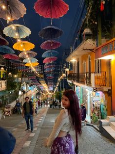 the woman is walking down the street with many umbrellas hanging from the ceiling above her