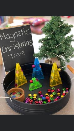 a christmas tree is in a tray with magnets on it and a sign that says magnetic christmas tree