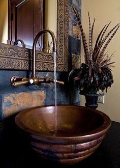 a bathroom sink sitting under a mirror next to a wooden bowl filled with flowers and plants