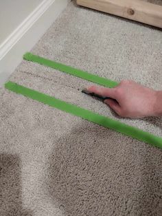 a person is using scissors to cut green tape on the carpet in front of a door