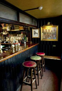 three stools are sitting at the bar in front of two framed pictures on the wall