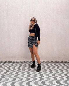 a woman standing in front of a wall wearing black and white checkered shorts with high heels