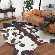 a living room with a couch, chair and cow hide rug